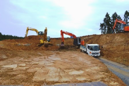広い工事現場でショベルカー3台とトラックが土を掘削している様子が写っている写真