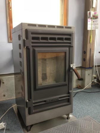 黒い金属製のペレットストーブが部屋の壁際に設置されている写真