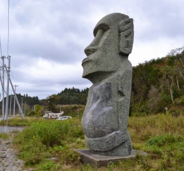 破損した部分がきれいに修復されたモアイ像が草地に立っている写真