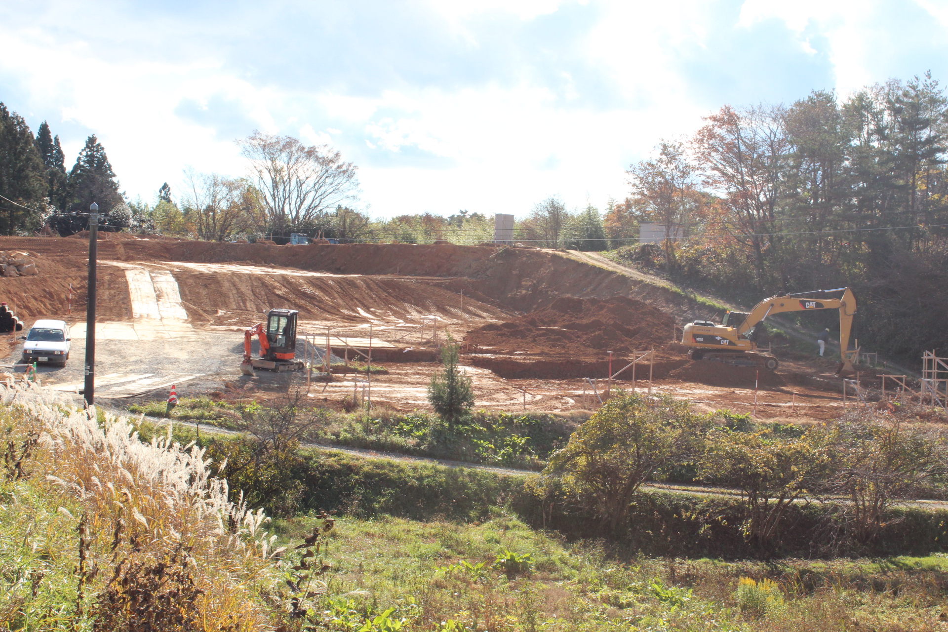 傾斜地を造成中で、重機が複数入り整地と区画整理が行われている造成地の写真