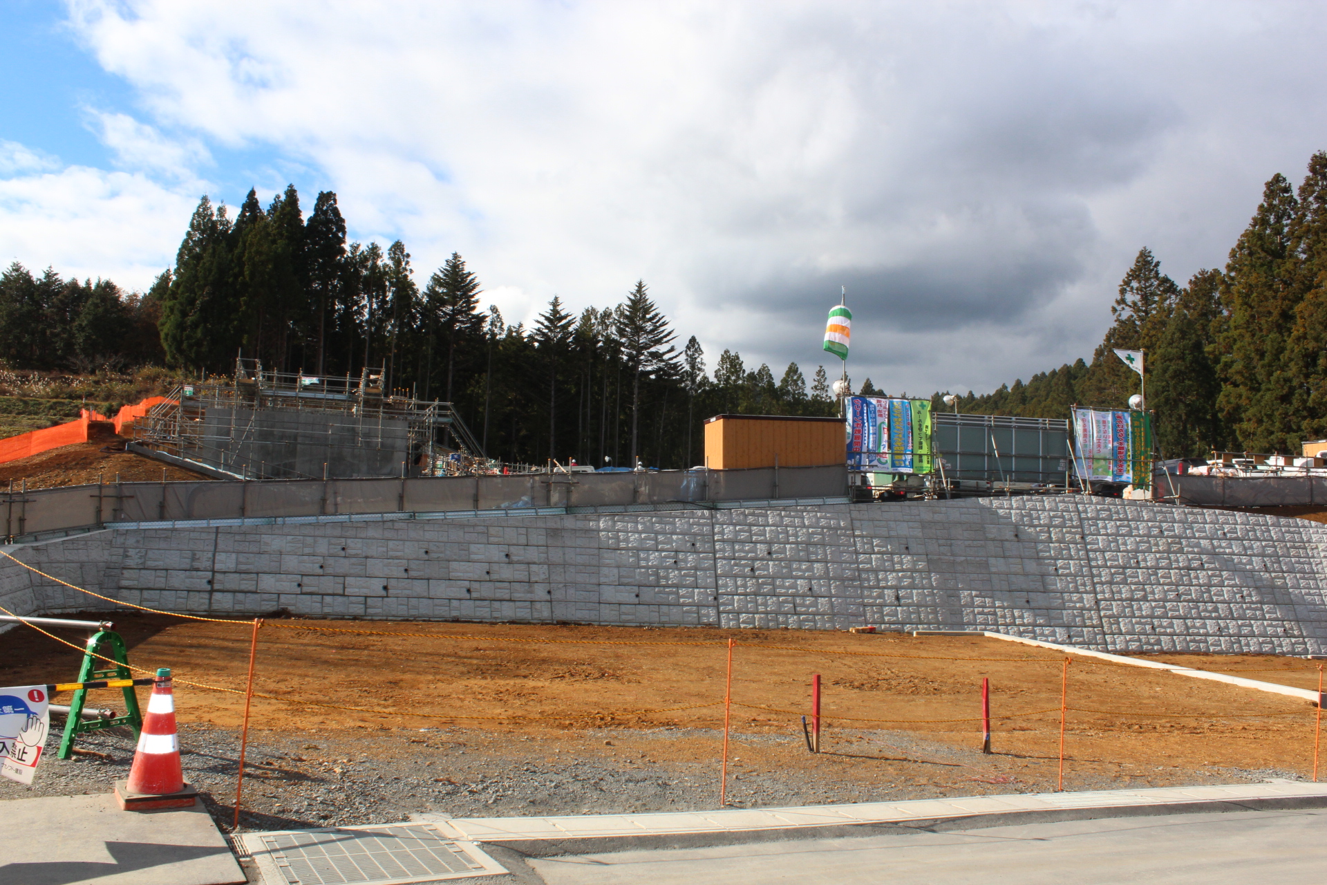 傾斜地に沿って積み上げられた石積み擁壁と、その上で建設作業が行われている様子の写真