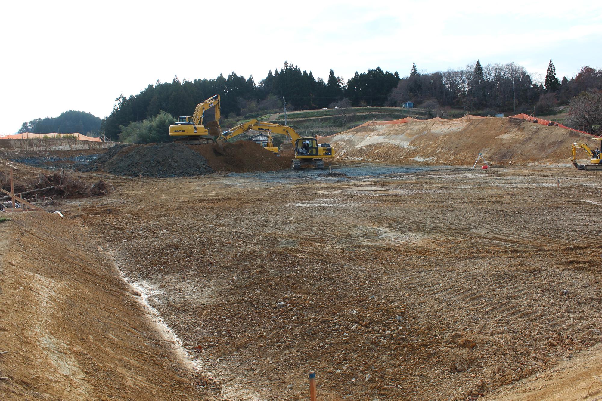 茶色い土が広がる敷地で複数のショベルカーが土を掘り起こしている造成工事中の写真