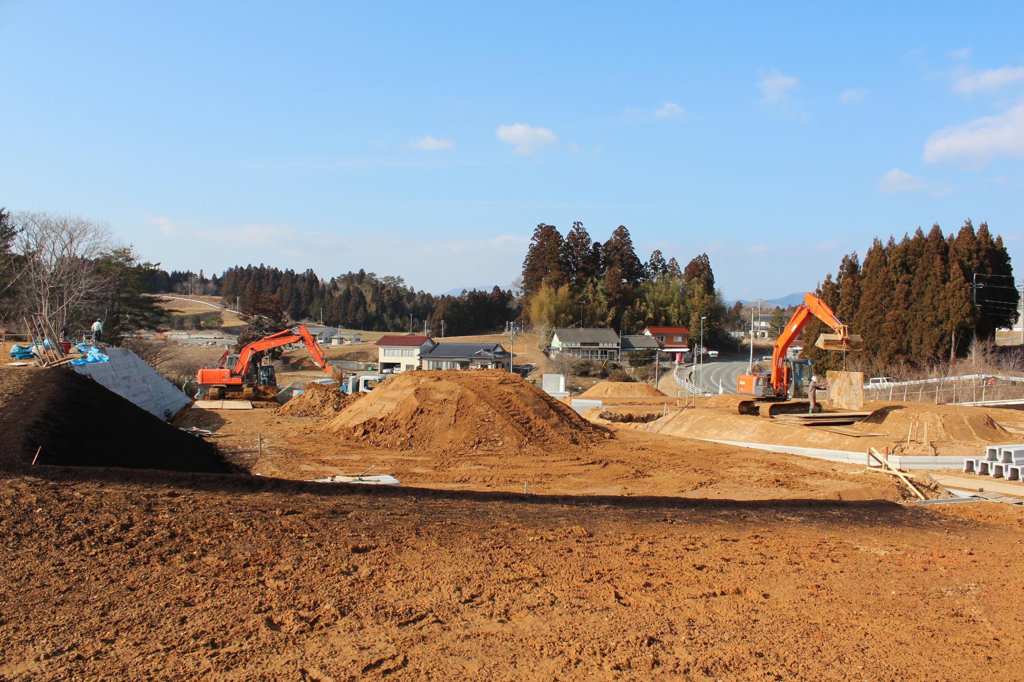 茶色い土が盛られた造成地で、複数のショベルカーが建設作業を進めている造成中の写真