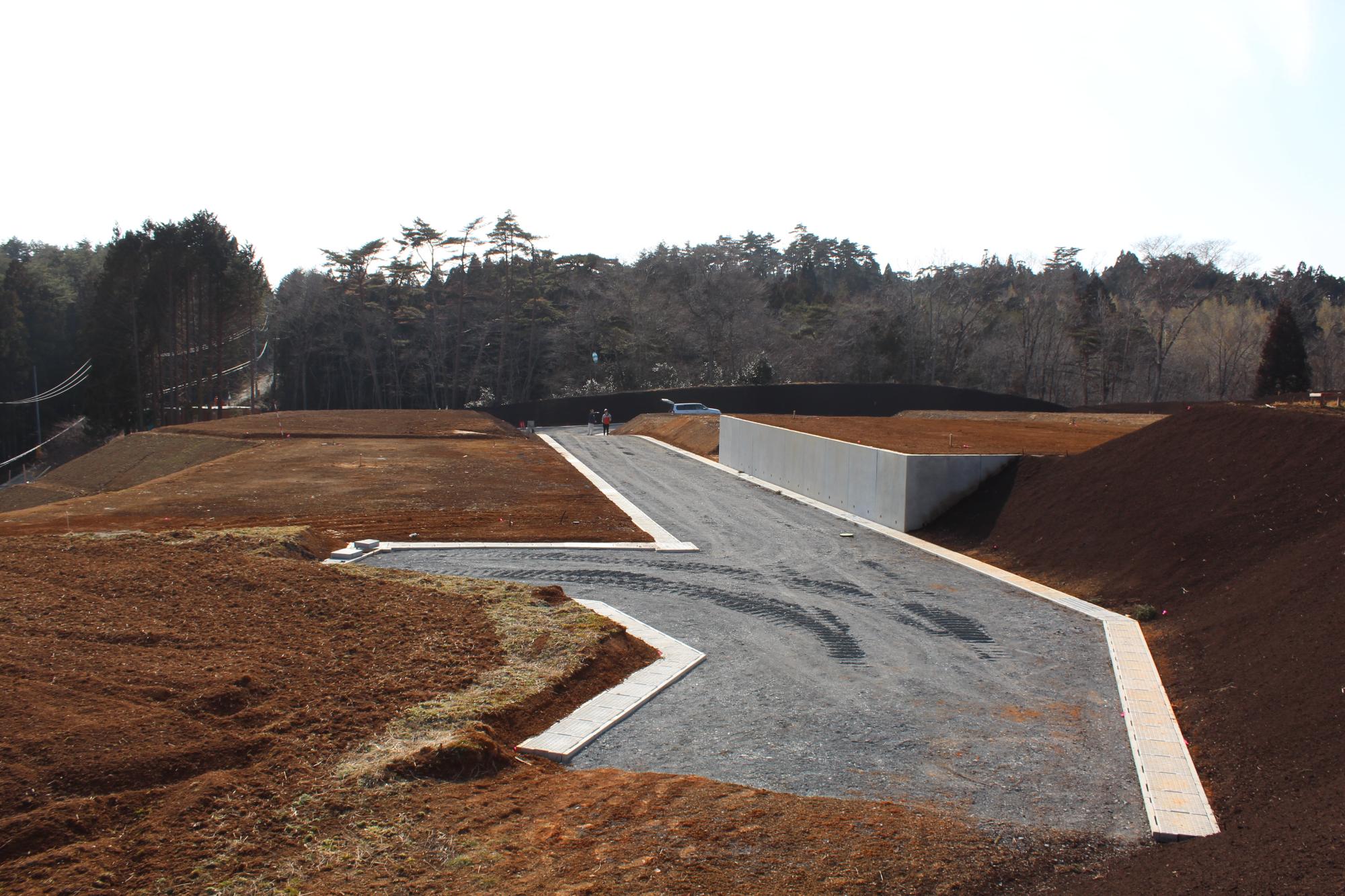 茶色い土の中に新しくできた交差点が見え、左右に整備中の区画が広がる宅地造成中の写真
