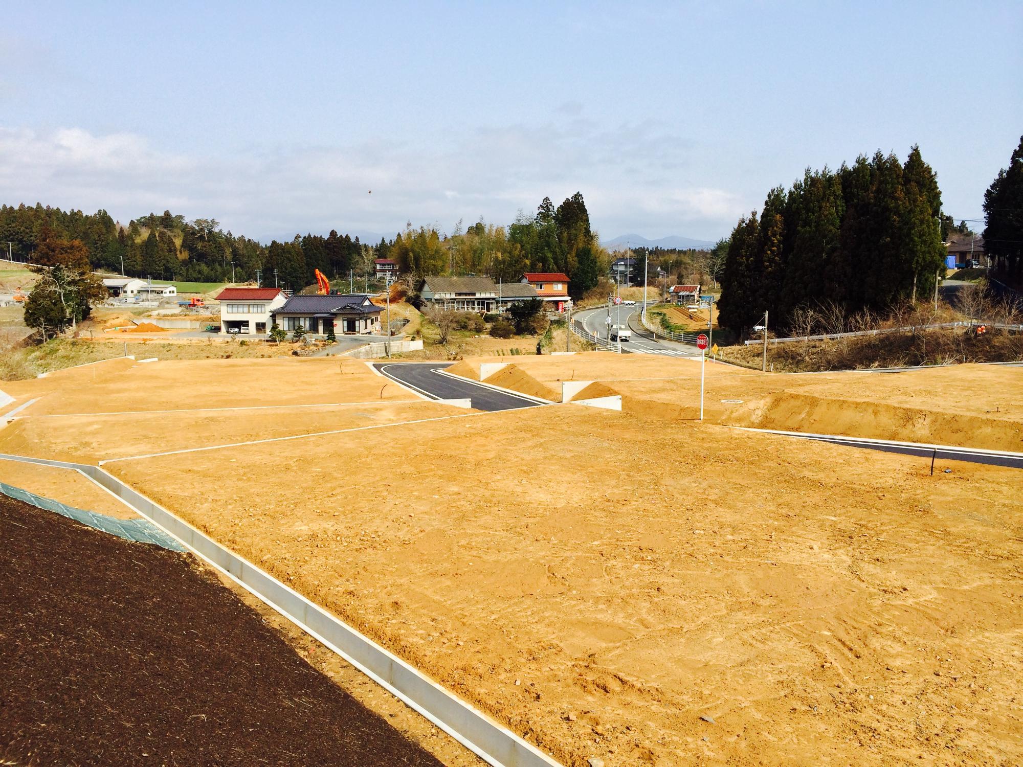 土が均された複数の宅地の間に道路が整備され、建設前の準備が整った状態の宅地造成後の写真