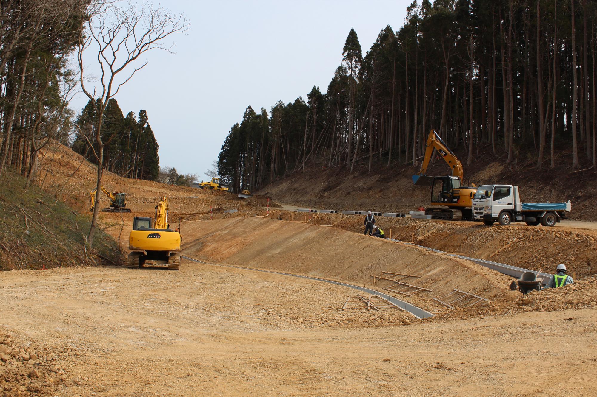 広大な土地で数台のショベルカーやトラックが稼働し、山を切り開いて道路や区画整備が進む造成工事中の写真