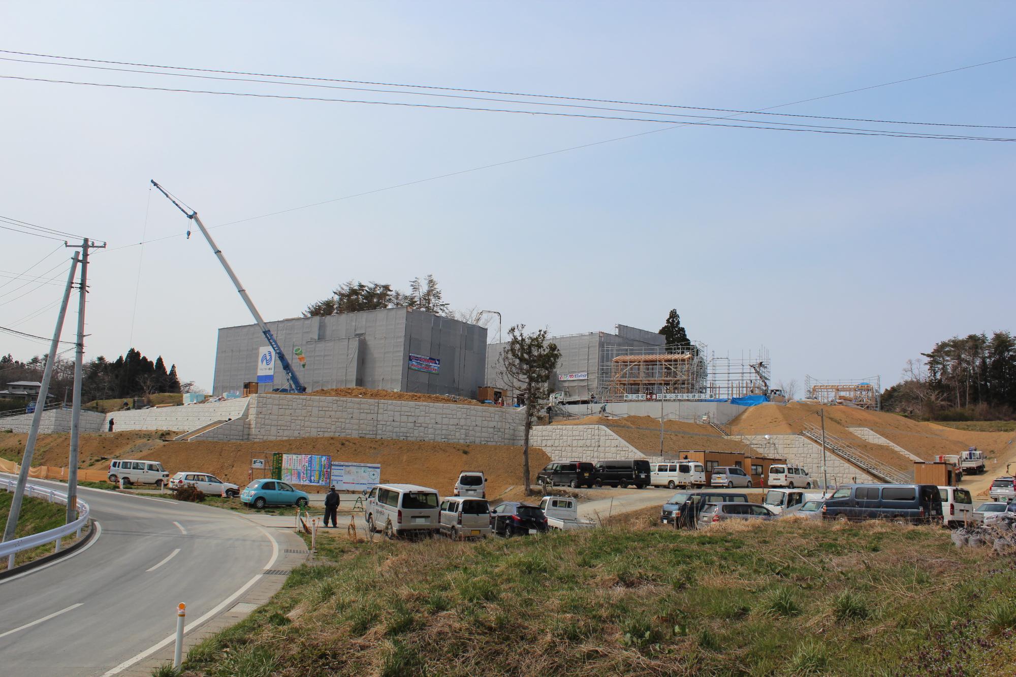 全体を見渡せる位置から撮影された高台に複数の建物が建設中の災害公営住宅の工事現場の写真