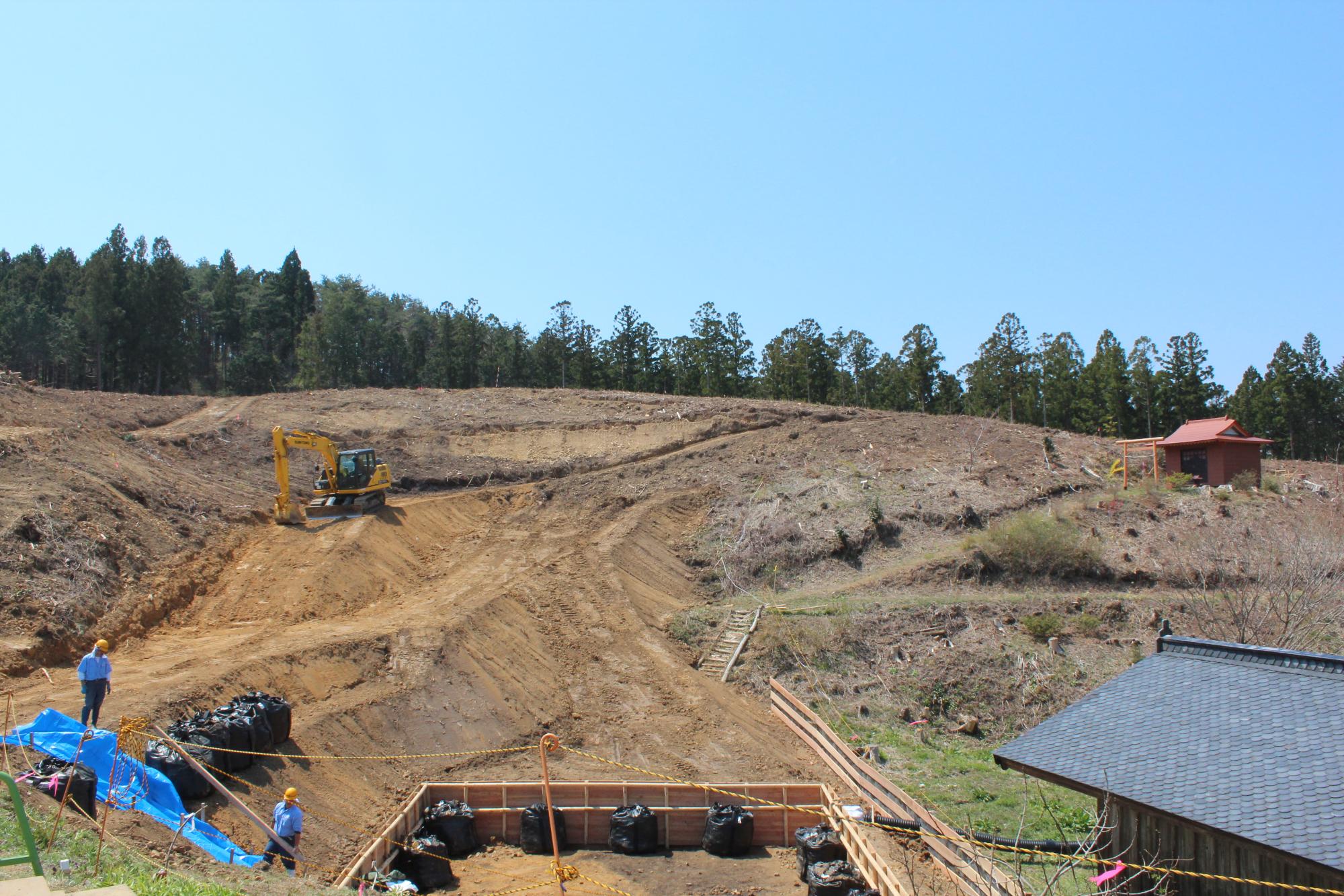 重機や作業員が山の斜面を整地している造成工事中の風景の写真
