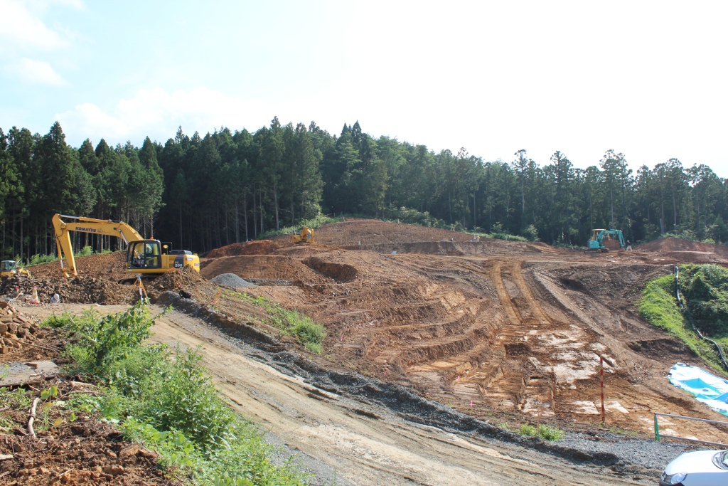 森林のそばで重機が使われ、斜面を段状に造成している工事現場の写真