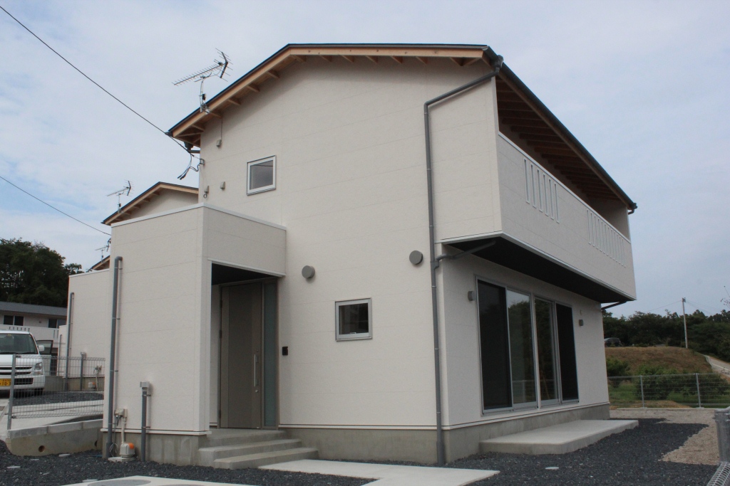 ベランダ付きのシンプルなデザインの2階建ての一戸建て住宅が完成した災害公営住宅の写真