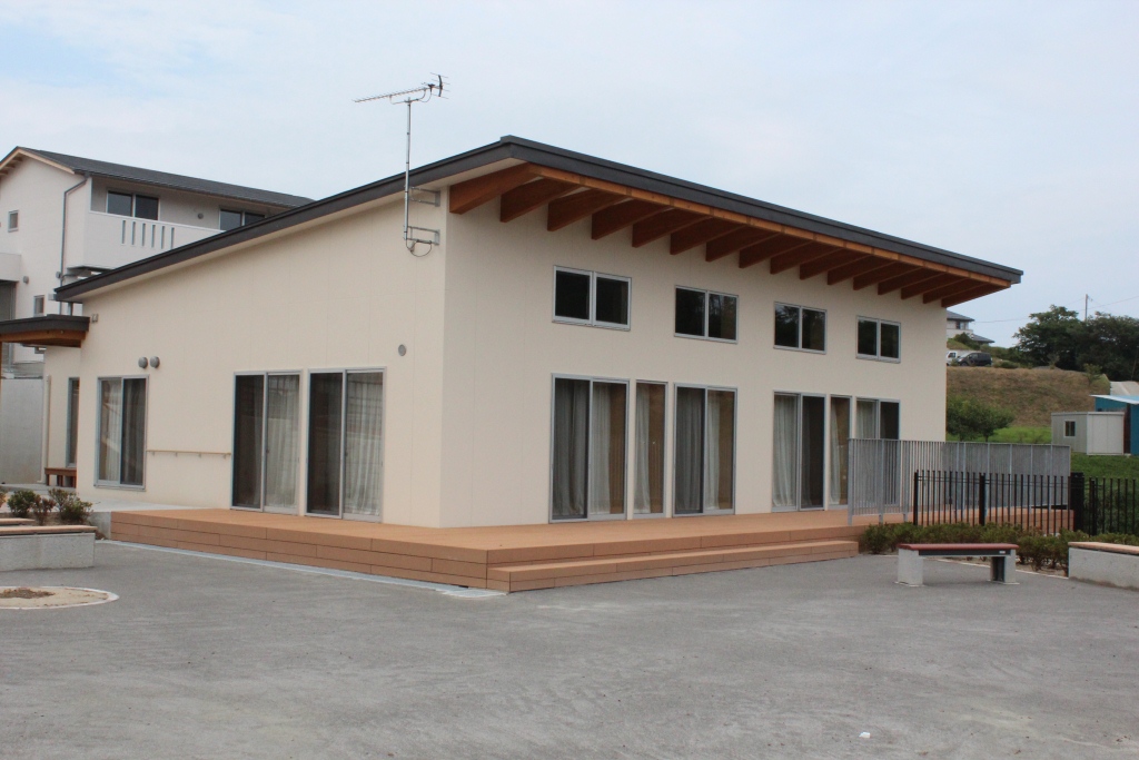 大きな窓とウッドデッキが特徴の平屋の集会場の様な建物の災害公営住宅の写真