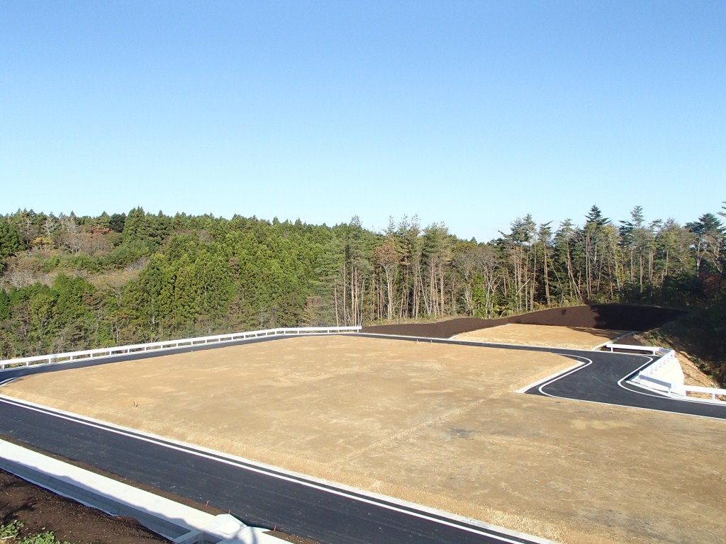 木々に囲まれた場所で、周囲をガードレールで囲まれた複数の区画が完成している造成地の写真