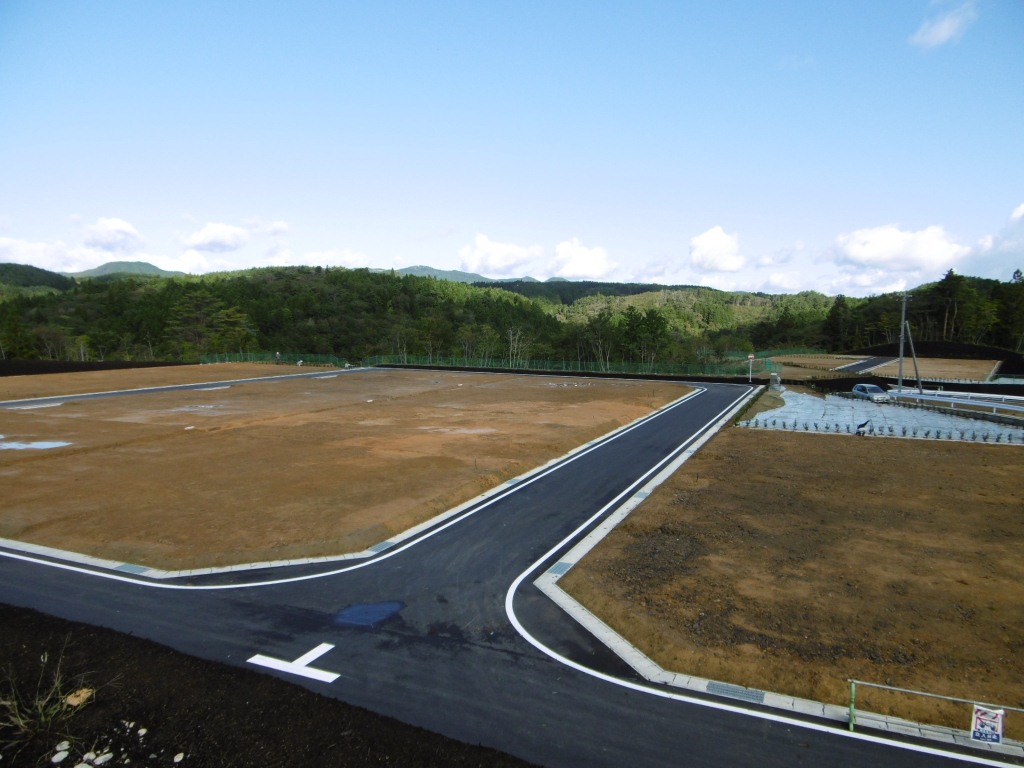 アスファルト舗装が完了し、区画が明確に整備された山間の造成地の写真