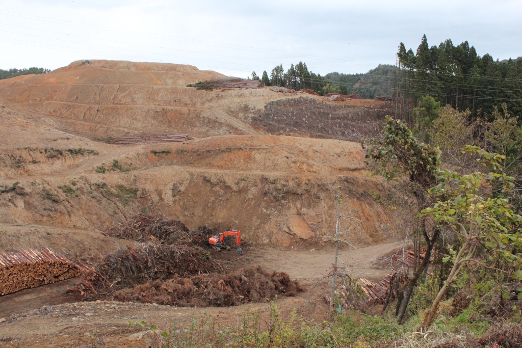 造成地の斜面付近に伐採された丸太などが積み上げられている写真