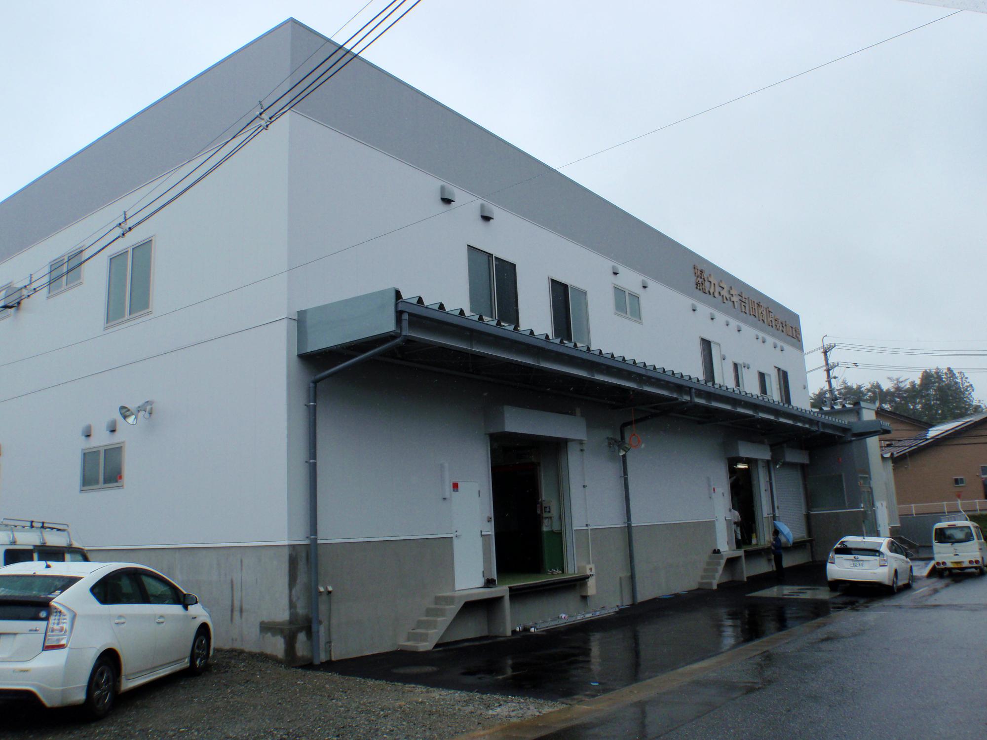 白い外壁で荷物の搬入口に屋根のある建物の外観写真