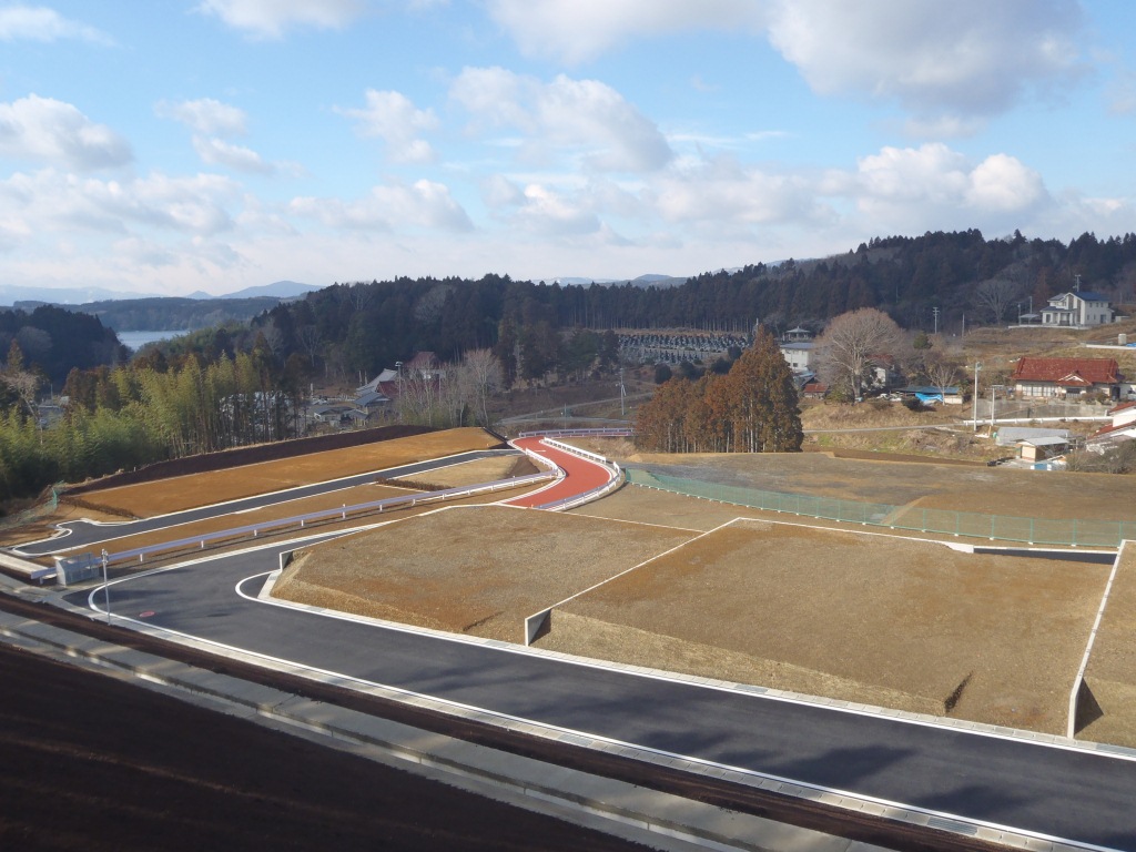 完成した宅地造成地に舗装された道路と盛土の区画が整然と配置された、晴天の宅地造成地完成後の写真
