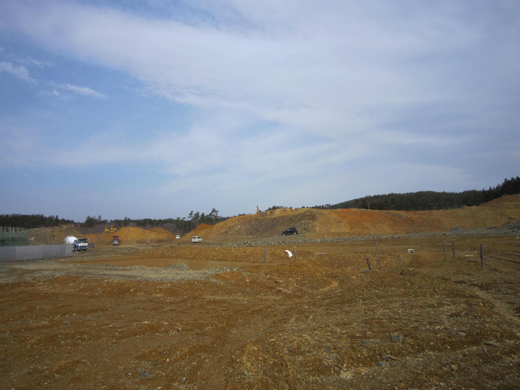 造成工事中の現場で重機やトラックが点在する広々とした土地の写真