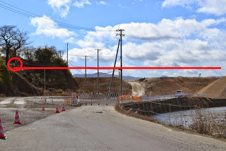 道路にはバリケードと交通コーンが設置されており、道路沿いには電柱と電線が並んで画像には赤い線が水平に引かれている写真