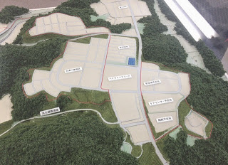 道路や区画の配置が明確に示されており、整備計画の全体像が見える、山林を切り開いた広い造成地の模型をアップで撮影した写真