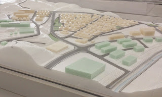 白と淡い緑色で構成された住宅地や施設、道路の配置と周囲の山の形状が再現されている立体模型の写真