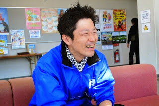 青いジャンバーを着たNaikiさんが笑顔でピンクのソファに座っている写真