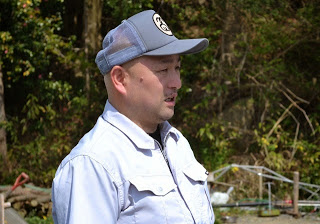 白い作業服にキャップを被った大沼さんが横を向いて立っている様子をアップで撮影した写真