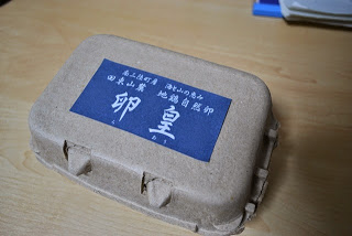 「卵皇」と書かれた青いラベルが貼られている段ボール製の卵パックの写真