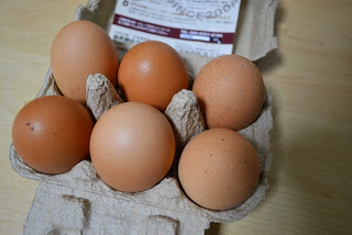 6個の茶色の卵がきれいに並んで入っている、卵パックの蓋を開けた状態の写真