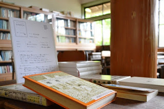 背景には本棚と窓が見える図書室の机の上に複数の本が並んでいるコーナーの写真