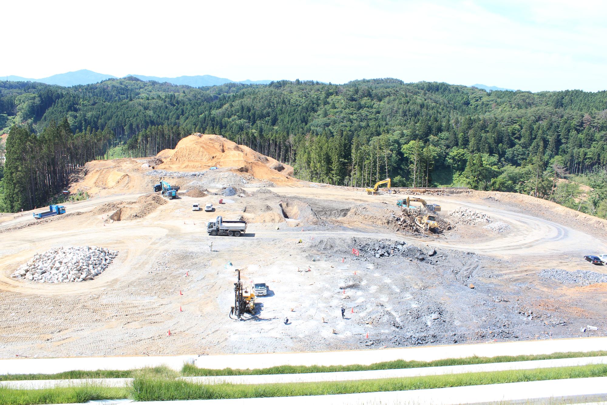 工事が進み、大量の重機とトラックが動き回り、砕石のエリアや大きく掘削された場所が見える造成工事中の写真