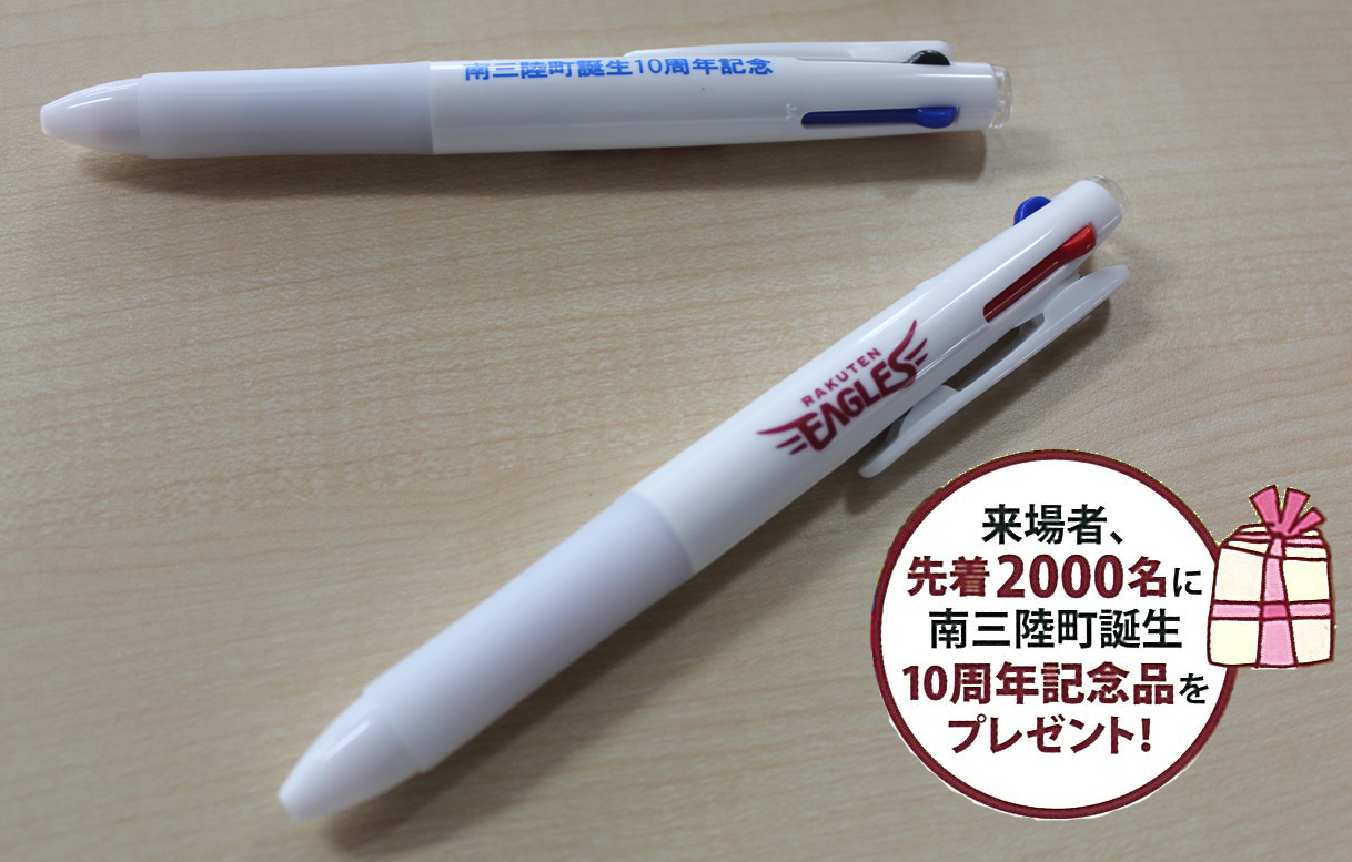 来場者、先着2000名に南三陸町誕生10周年記念品をプレゼント！の文字と白地に青色の文字、白地に赤色の文字が入った2種類のボールペンが置かれている写真