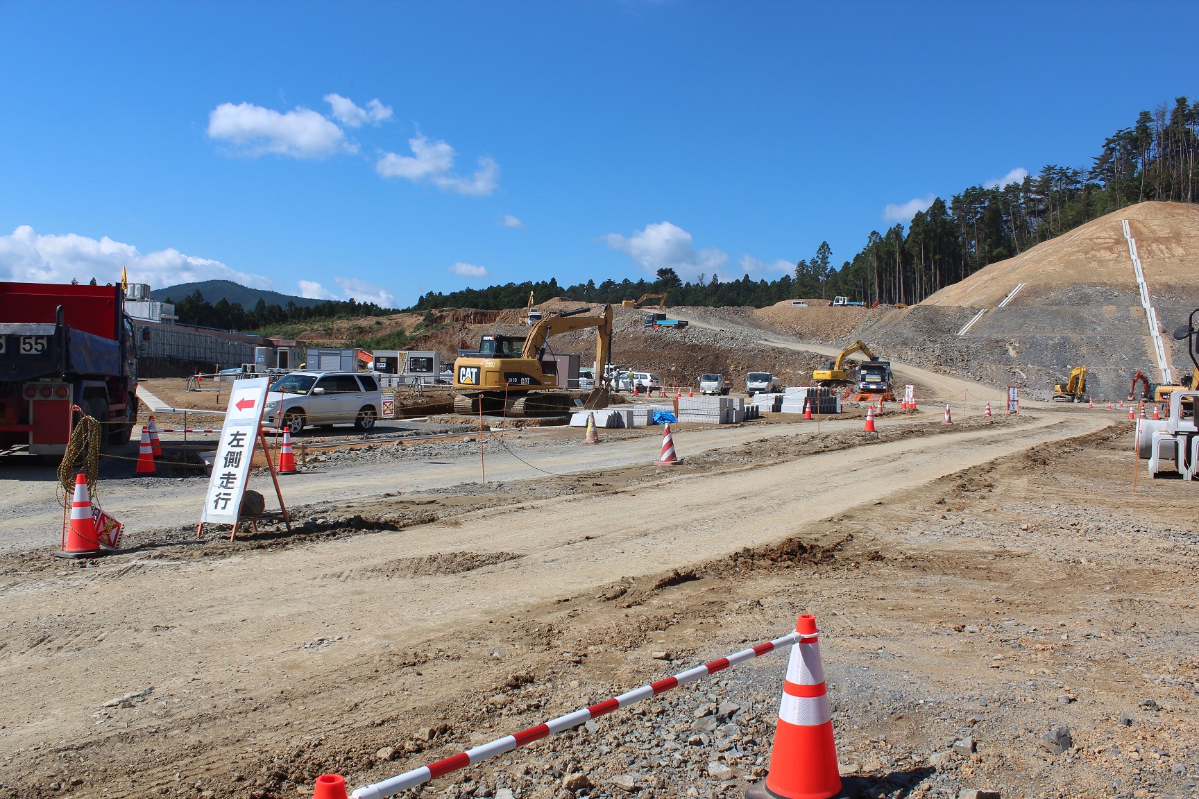 晴天の下で工事が進む造成地と「左側通行」と書かれた看板がある写真