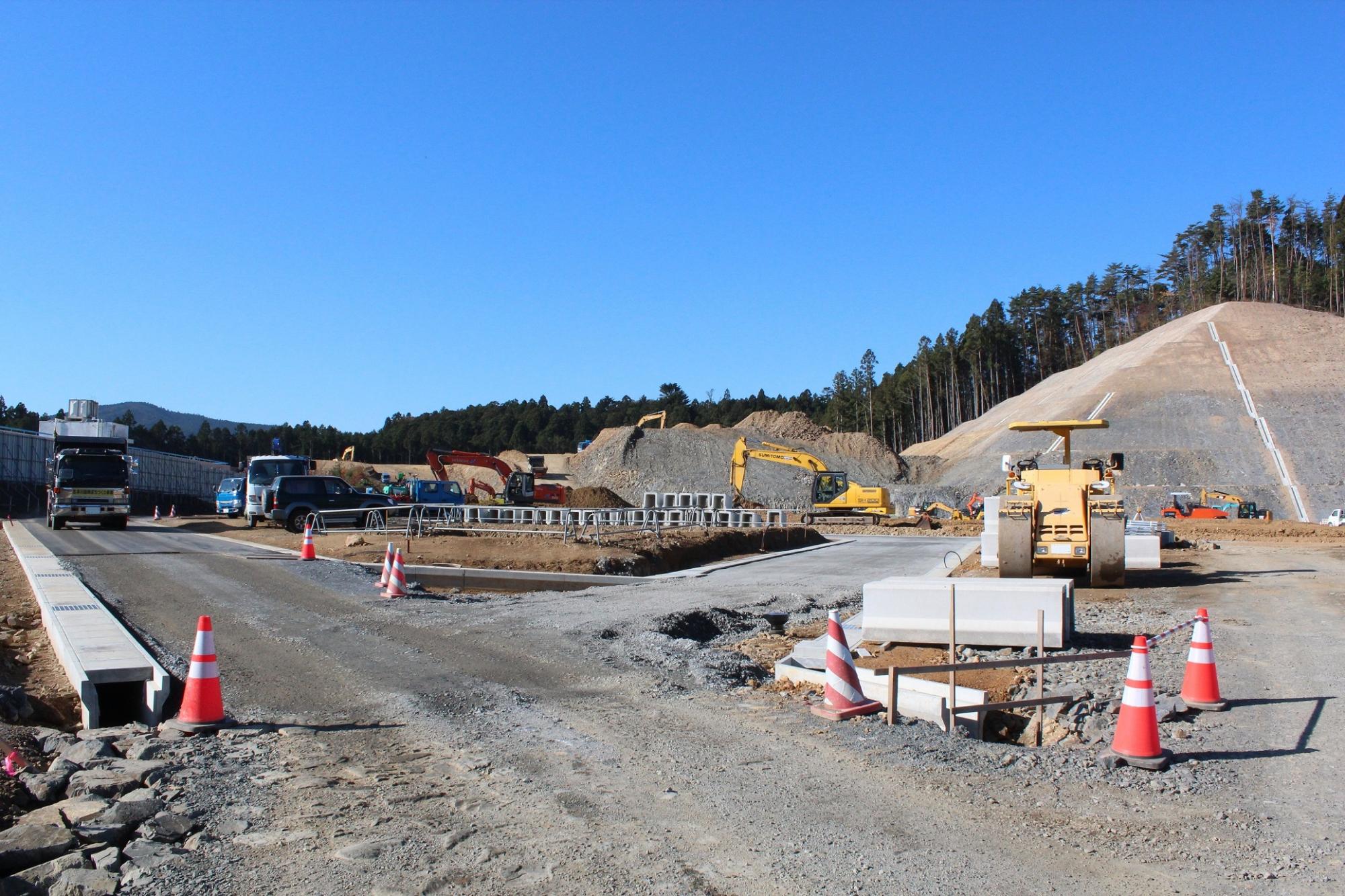 舗装が進み始めた造成地で大型ローラー車が見える工事現場の写真