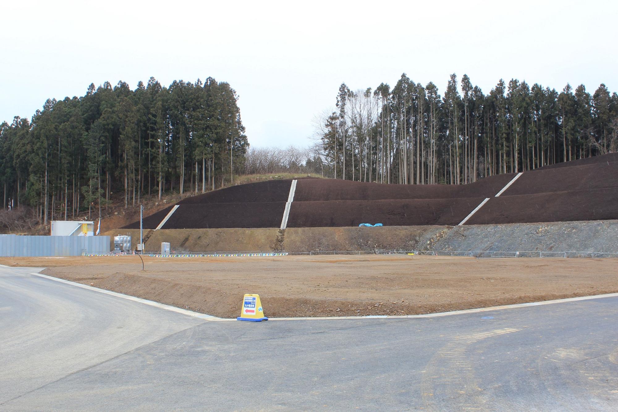 黒い土で整えられた法面と空き地が広がる造成地の写真