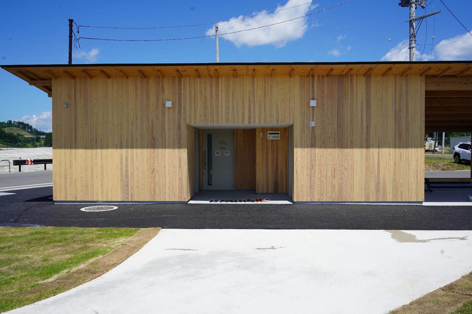 木目調の外壁に平らな屋根が特徴的なモダンな建物の公衆用トイレを正面から写した写真