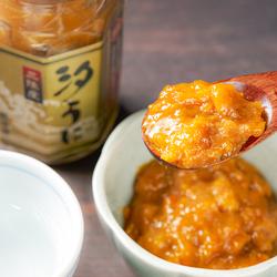 木製のスプーンで白い器の中のペースト状の汐うにをすくっている写真