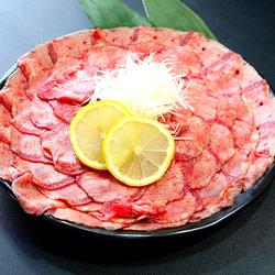 大きな黒い皿の上に、薄くスライスされた生の牛肉が円を描くように並べられている写真