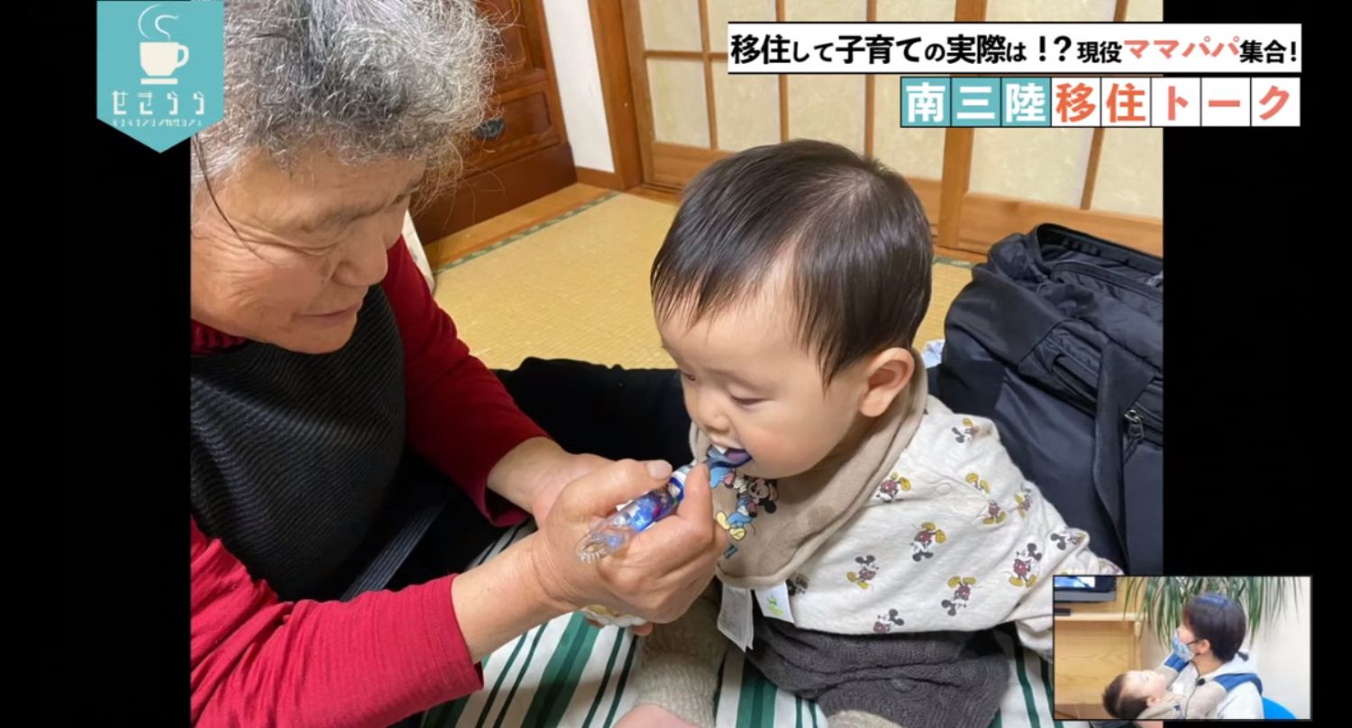 「移住して子育ての実際は！？現役ママパパ集合！南三陸移住トーク」のテーマタイトルが画面右上に表示されており、赤い服を着たおばあさんが、ミッキーマウス柄の服を着た赤ちゃんにスプーンで食事をあげている様子の映像と右下のワイプ画像に赤ちゃんを抱いた女性が映っているYouTube LIVE配信番組のスクリーンショットの写真