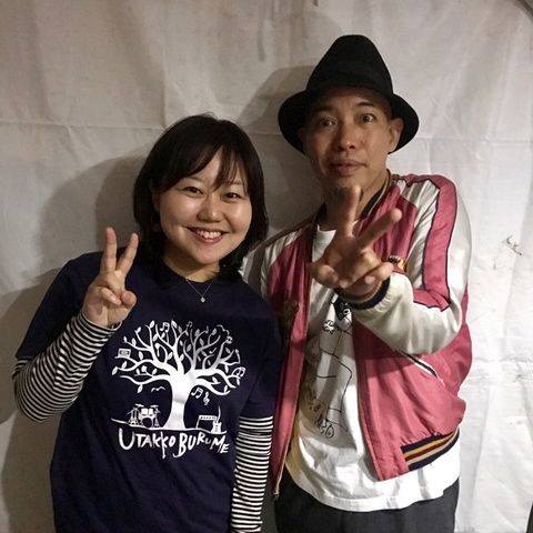 白い布を背後に、前川さんと女性リポーターが並んでピースサインをしている写真