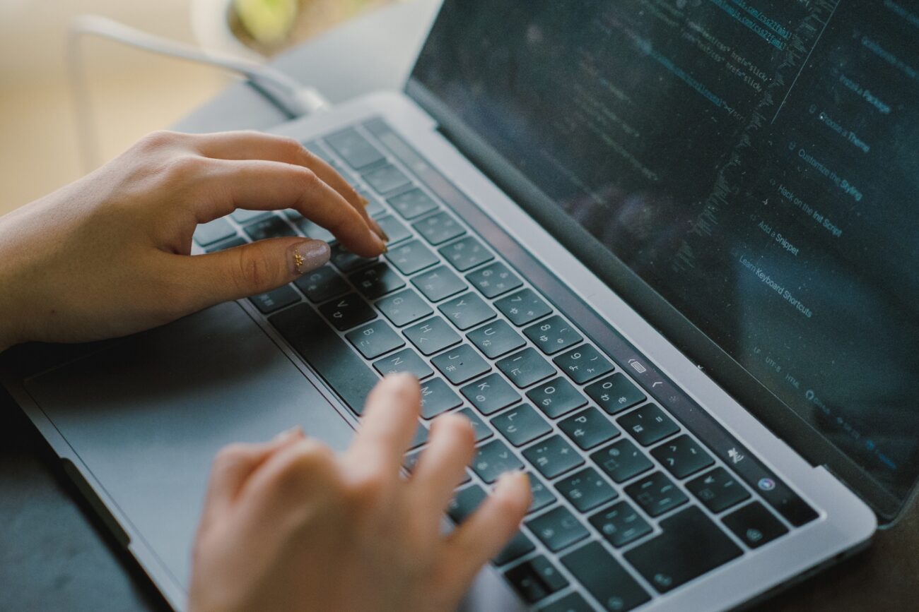 ノートパソコンのキーボードをタイピングしている手元の写真