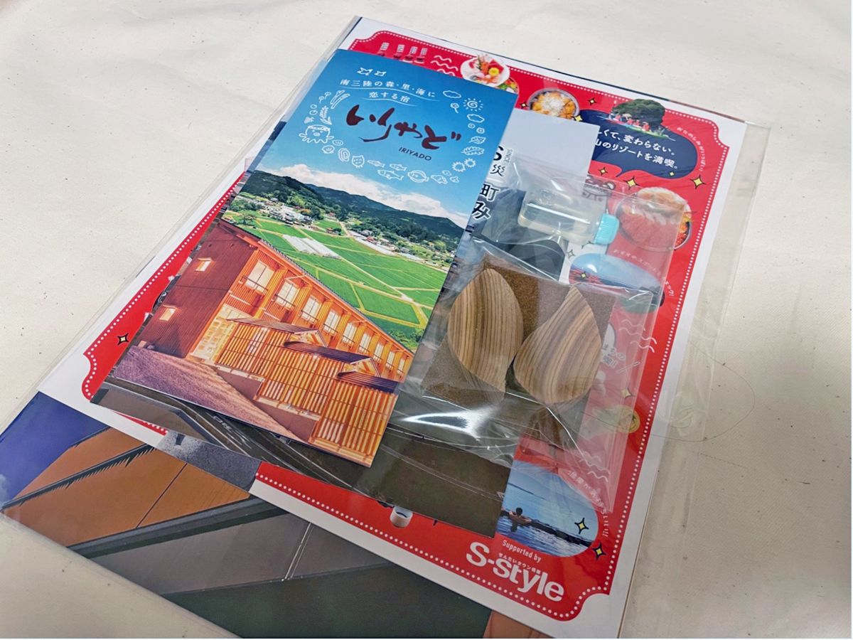 透明な袋に、観光パンフレットや木の工作キット、小さなプラスチック容器などが詰め合わされている記念品セットの写真