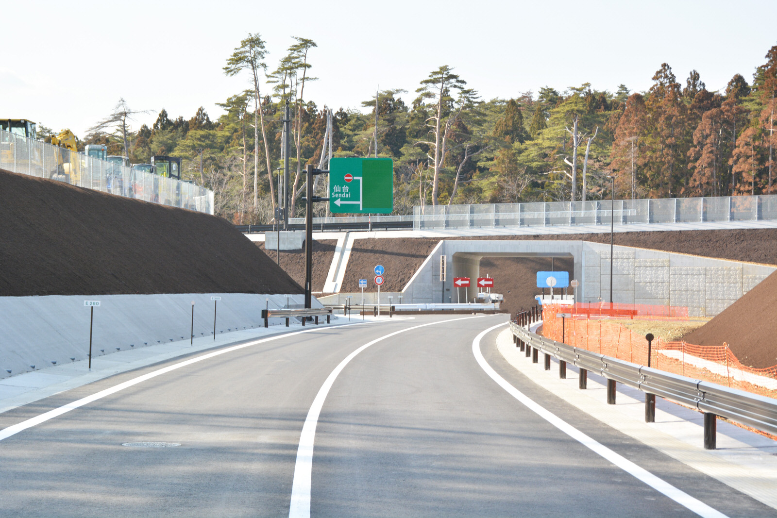 新しく整備された三陸沿岸道路がカーブしながら続いており、緑色の標識やトンネルが見える写真