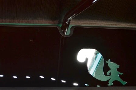 背景が黒でリスが歩いた足跡と大きなしっぽをゆらしながら右方向にあるいている白いリスの写真