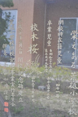 桜の花の彫刻とともに、閉校記念の文字や開校当時の情報が刻まれた石碑をアップで撮影した写真