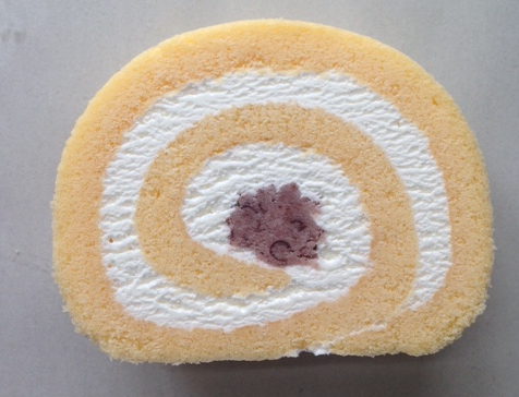 黄色い生地に白いクリームが渦状に巻かれ、中心にあんこが入っているロールケーキの断面の写真