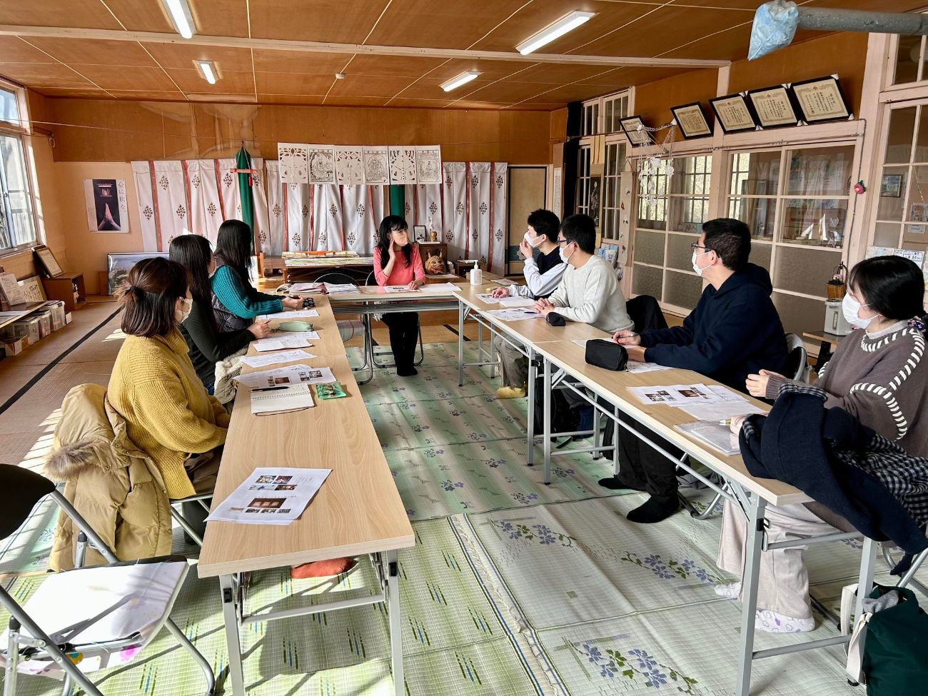 会議室で8人がテーブルを囲み、真剣に話し合っている場面の写真