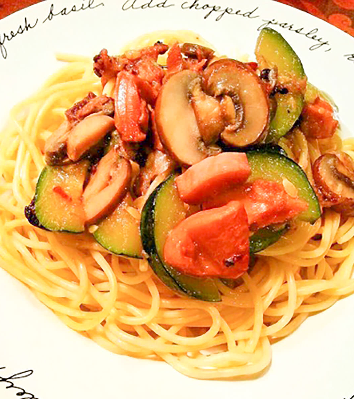 縁にローマ字が書かれたデザインの白い皿に盛り付けられた、タコ、ズッキーニ、マッシュルームが入ったタコのアヒージョパスタの写真