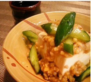 冷ややっこの上に納豆ときゅうりをトッピングした料理を、斜めの角度から撮影した写真