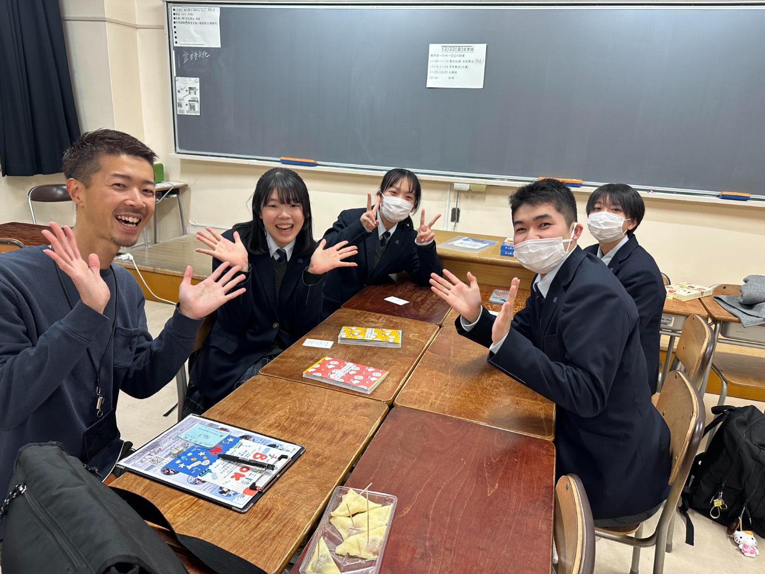 教室で制服姿の高校生たちが笑顔で座り、ボードゲームを囲んで地域について楽しく学ぶ活動をしている写真