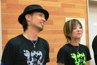 黒いTシャツを着た歌の上村美保子さんとベースのJIGENさんが並んで笑顔で立っているの写真